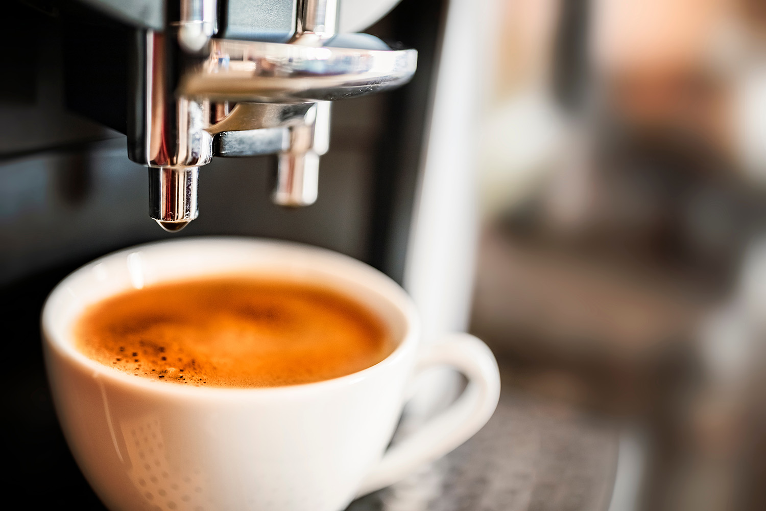 A fresh shot of espresso with golden crema pulling from an espresso machine